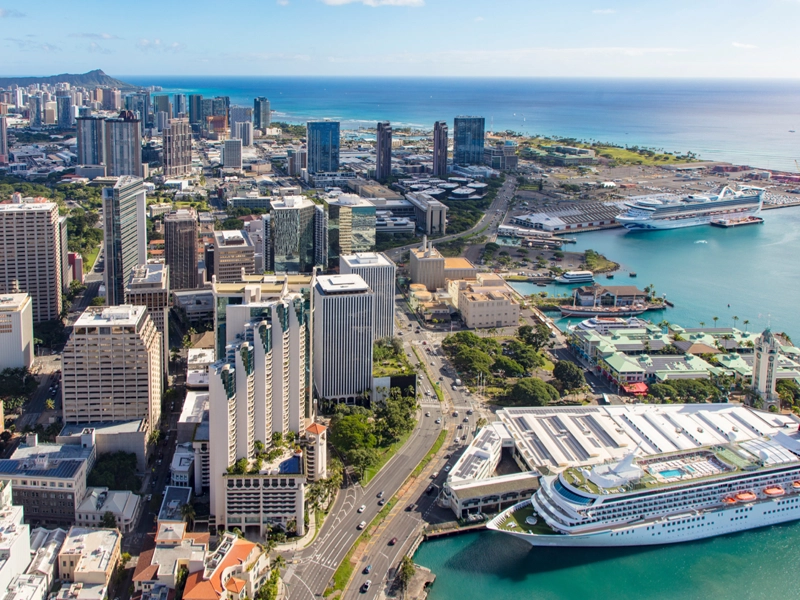 A picture of a cruise ship pulling into a busy port in Hawaii